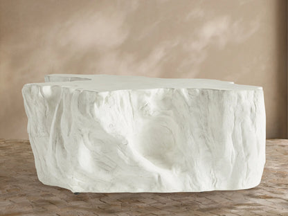 Bleached Root Outdoor Coffee Table, light concrete, organic shape, textured sides, flat top, on brick floor.