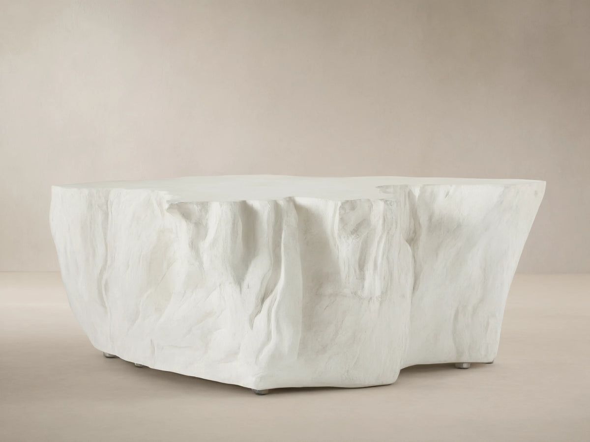 Bleached Root Outdoor Coffee Table, light concrete, organic shape, textured sides, flat top, on brick floor.
