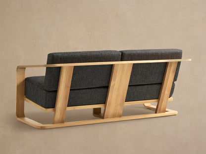 Sonoma Outdoor Teak Sofa, close-up of natural teak frame with rounded arm and dark gray flecked cushions.