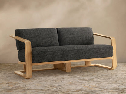 Sonoma Outdoor Teak Sofa, front view. Light natural teak wood frame, two dark gray textured cushions on seat and back.