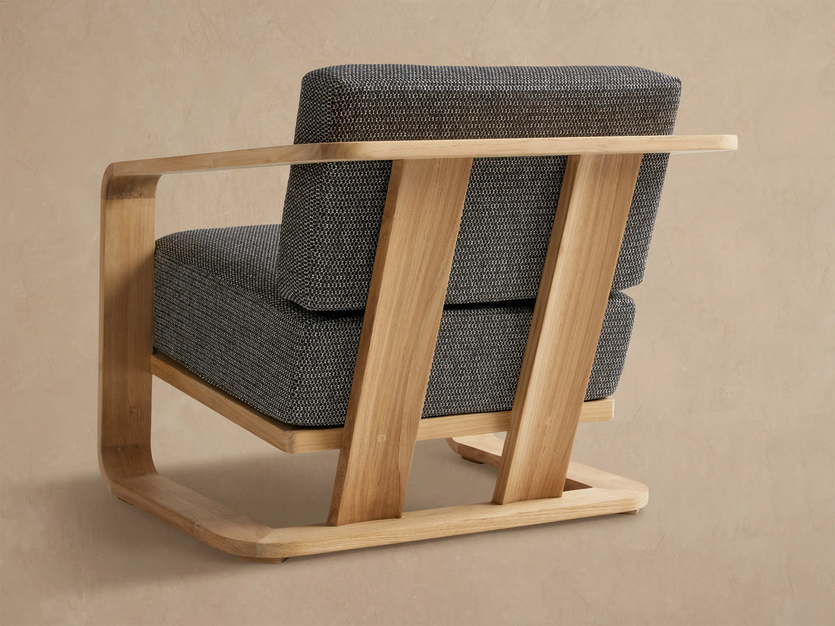 Close-up of Sonoma Teak Lounge Chair's smooth, light teak wood armrest and speckled gray and white outdoor cushion.
