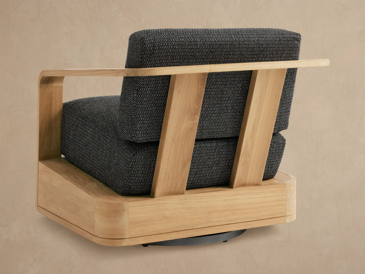 Sonoma Outdoor Teak Swivel Chair with light teak wood frame and dark grey textured cushions, side angle.