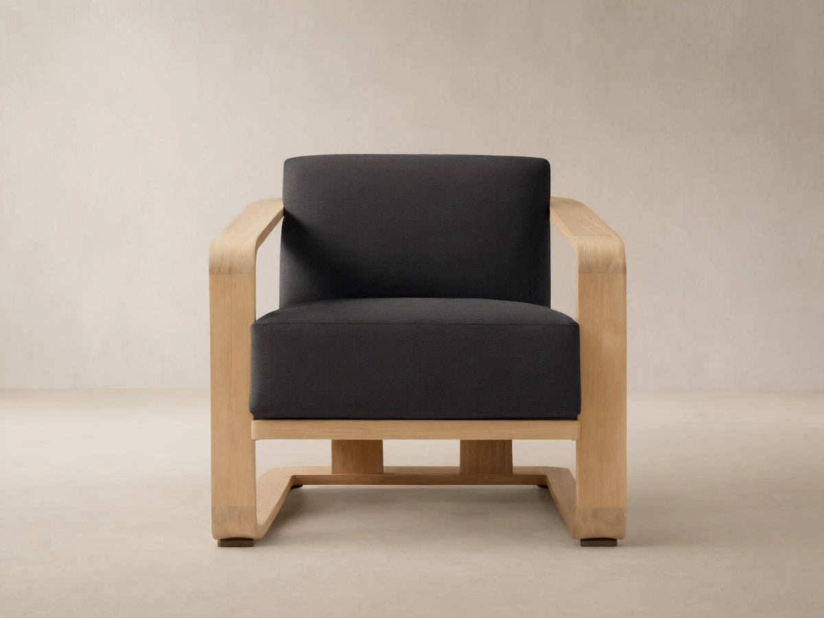 Sonoma Outdoor Lounge Chair with a light teak frame and deep Rosemount Graphite cushions, front view on a stone patio.