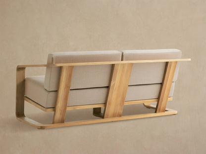 Sonoma Outdoor Teak Sofa. Close-up of light natural teak wood armrest with visible grain, light cream fabric seat and back cushions.