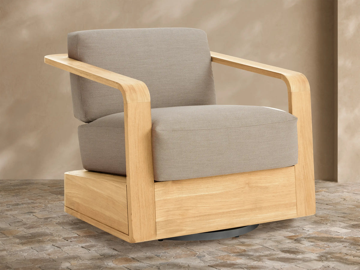 Sonoma Outdoor Teak Swivel Chair with light natural teak frame & light gray cushions, angled view on tiled patio.