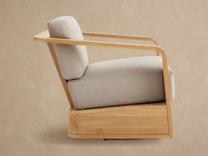 Sonoma Outdoor Teak Swivel Chair; close-up of natural golden teak frame, curved armrest, and light tan fabric cushions.