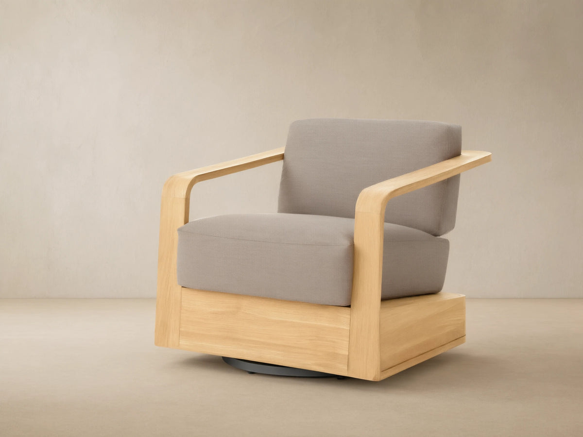 Sonoma Outdoor Teak Swivel Chair with light natural teak frame & light gray cushions, angled view on tiled patio.