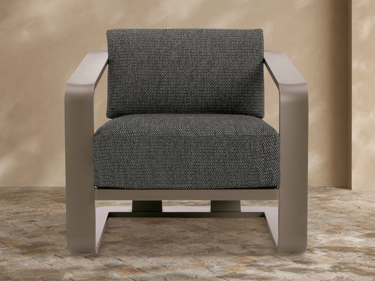 Sonoma Outdoor Aluminum Lounge Chair with dark taupe frame & dark gray textured cushions, viewed from front-right on a stone patio.