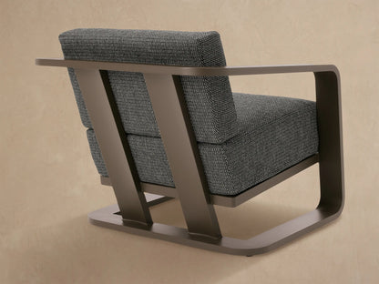 Close-up of Sonoma outdoor lounge chair's smooth brown aluminum armrest and textured dark grey fabric cushions.