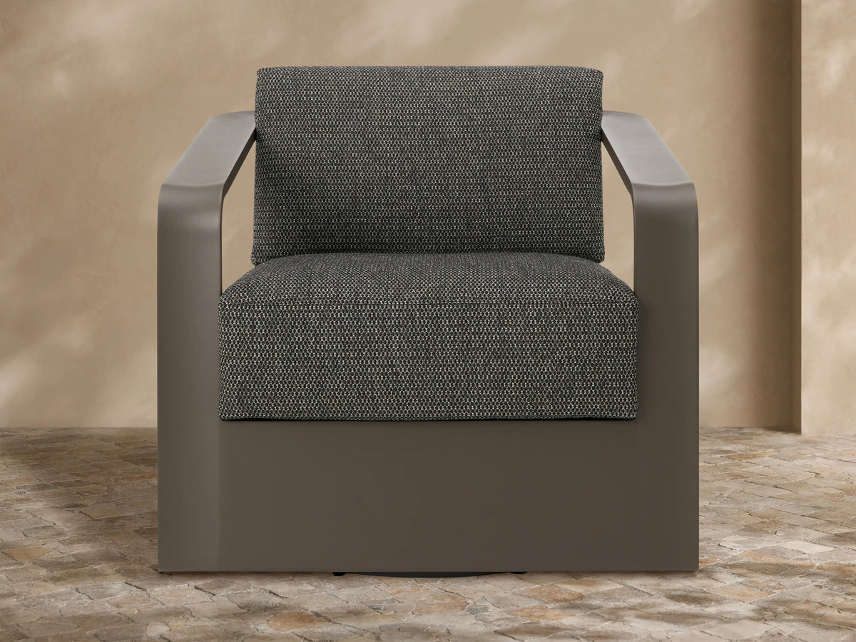 Angled Sonoma Outdoor Aluminum Swivel Chair with dark grey frame & textured grey cushions, on a stone patio.