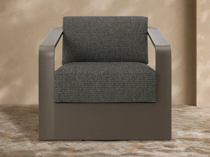 Angled Sonoma Outdoor Aluminum Swivel Chair with dark grey frame & textured grey cushions, on a stone patio.