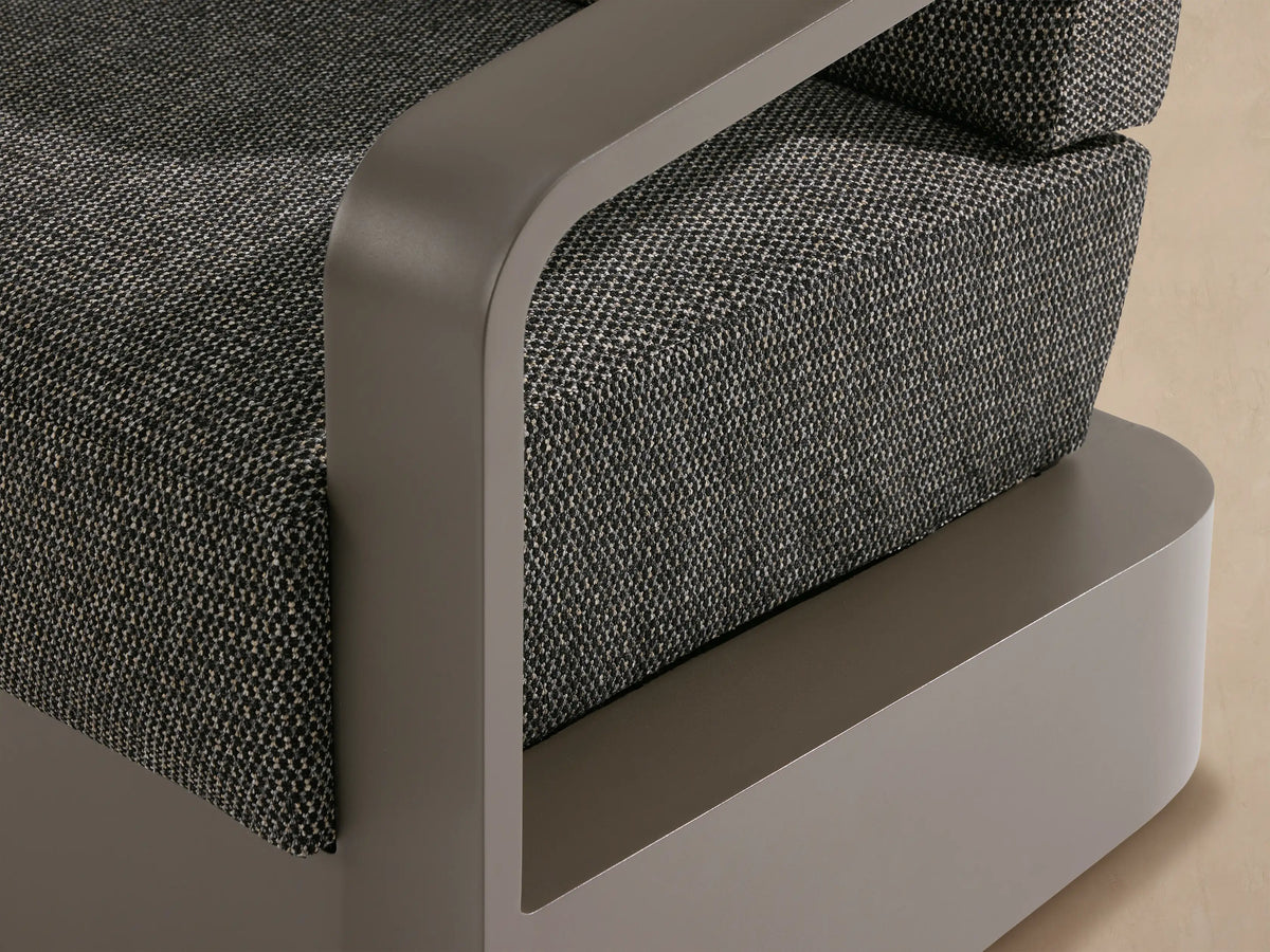 Front view of Sonoma Outdoor Swivel Chair. Powder-coated gray aluminum frame, charcoal gray woven cushions on a light stone patio.