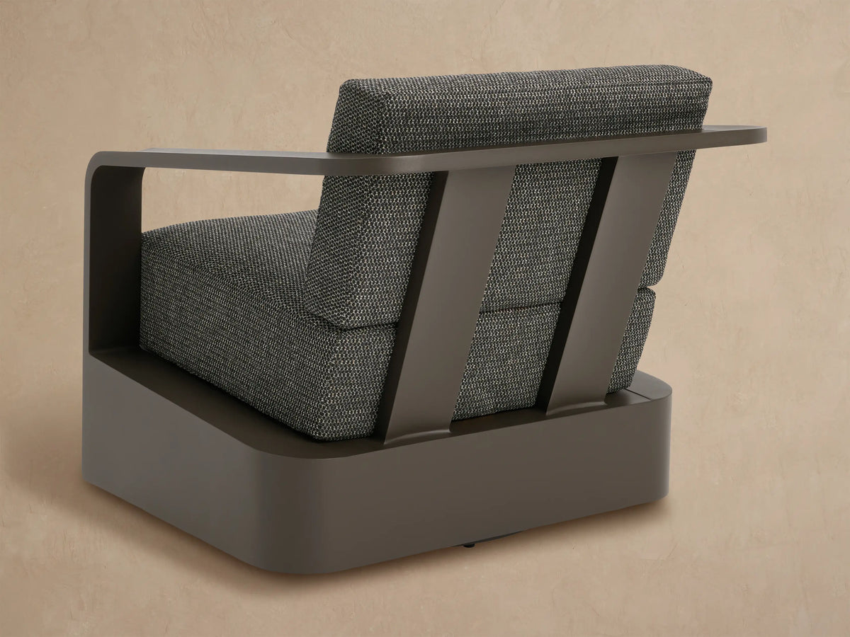 Close-up of Sonoma Swivel Chair. Matte bronze aluminum frame with speckled charcoal woven fabric cushions & curved armrest.