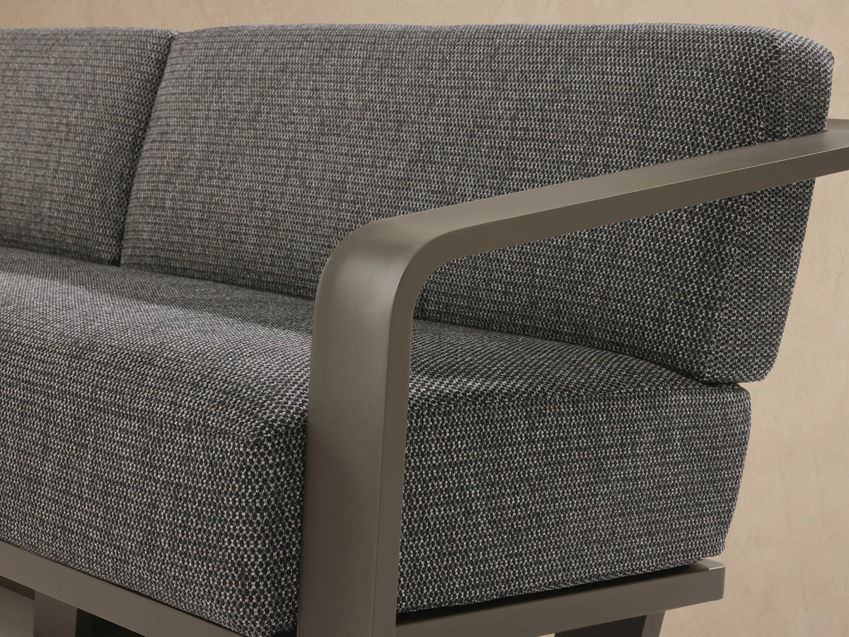 Sonoma Outdoor Aluminum Sofa, 2-seater, with charcoal cushions & a dark aluminum frame, outdoors on a stone patio.