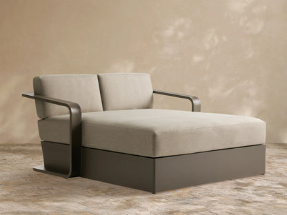 Angled Sonoma Outdoor Aluminum Daybed with light beige cushions and a dark bronze frame on a patio.