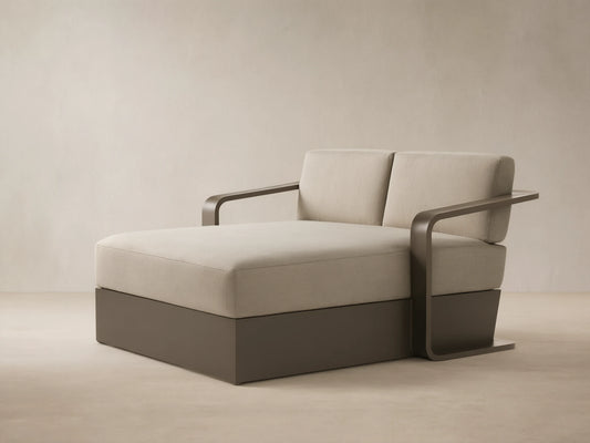 Angled Sonoma Outdoor Aluminum Daybed with light beige cushions and a dark bronze frame on a patio.