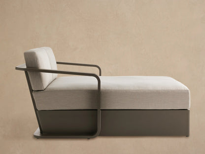 Angled Sonoma Outdoor Aluminum Daybed with light beige cushions and a dark bronze frame on a patio.