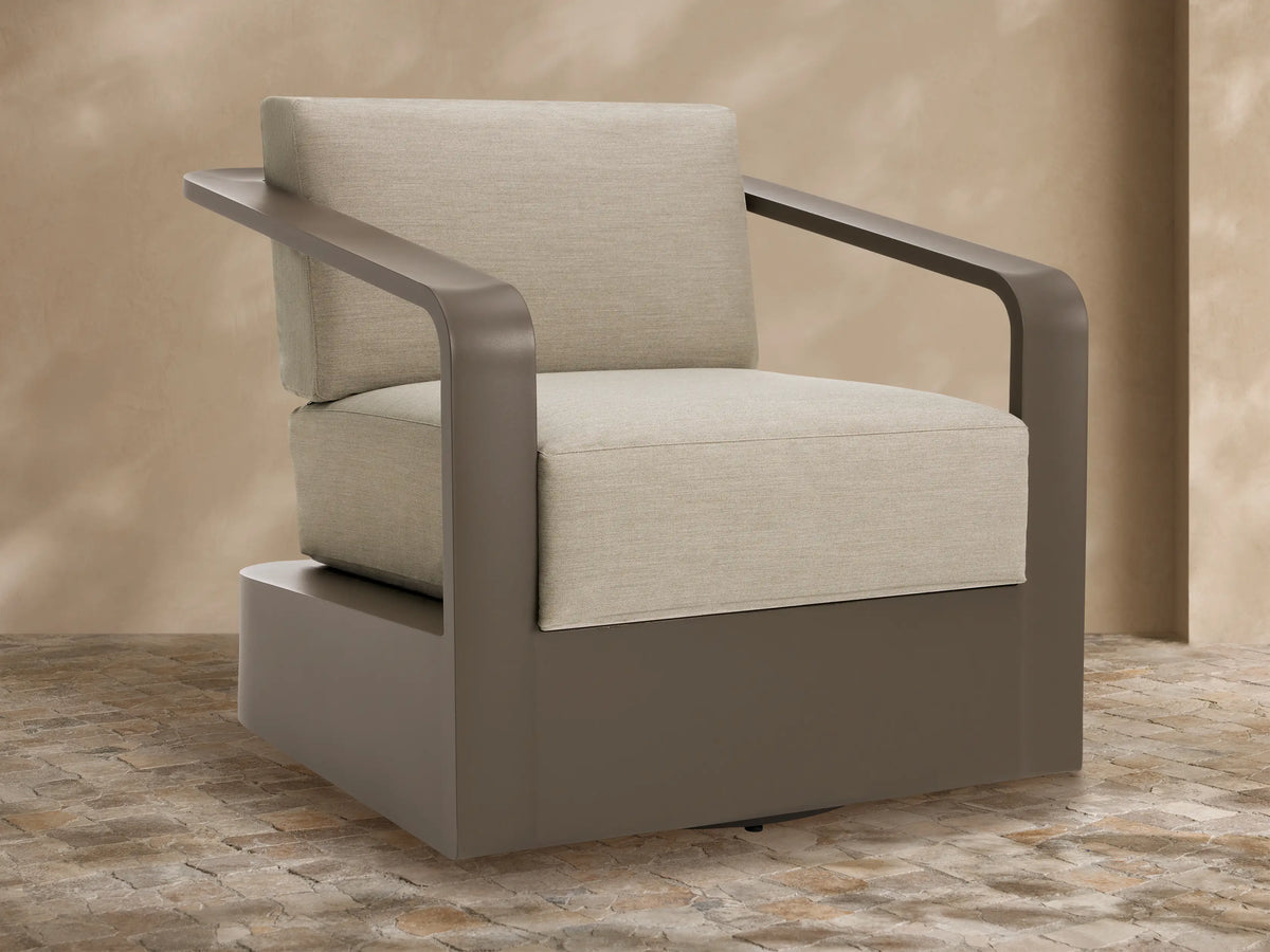 Sonoma Outdoor Aluminum Swivel Chair with sleek brown frame and thick, light beige cushions on a stone patio.