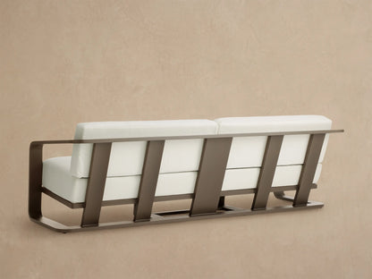 Angled close-up of Sonoma Outdoor Aluminum Sofa with curved dark bronze frame and plush white Savona Snow cushions.