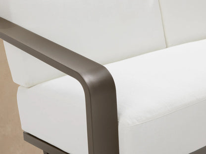 Sonoma Outdoor Aluminum Sofa with a modern dark gray frame and two white cushions, viewed at an angle on a patio.