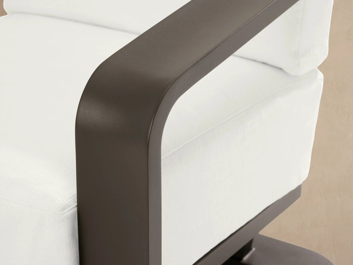 Sonoma Outdoor Aluminum Lounge Chair, frontal. Dark gray frame, thick white Savona Snow cushions, on a stone patio.