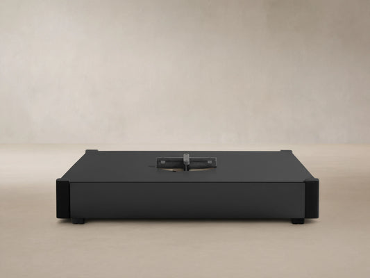 Black rectangular Spectra Outdoor Umbrella Base with a central silver cross-shaped mounting plate against a light wall.
