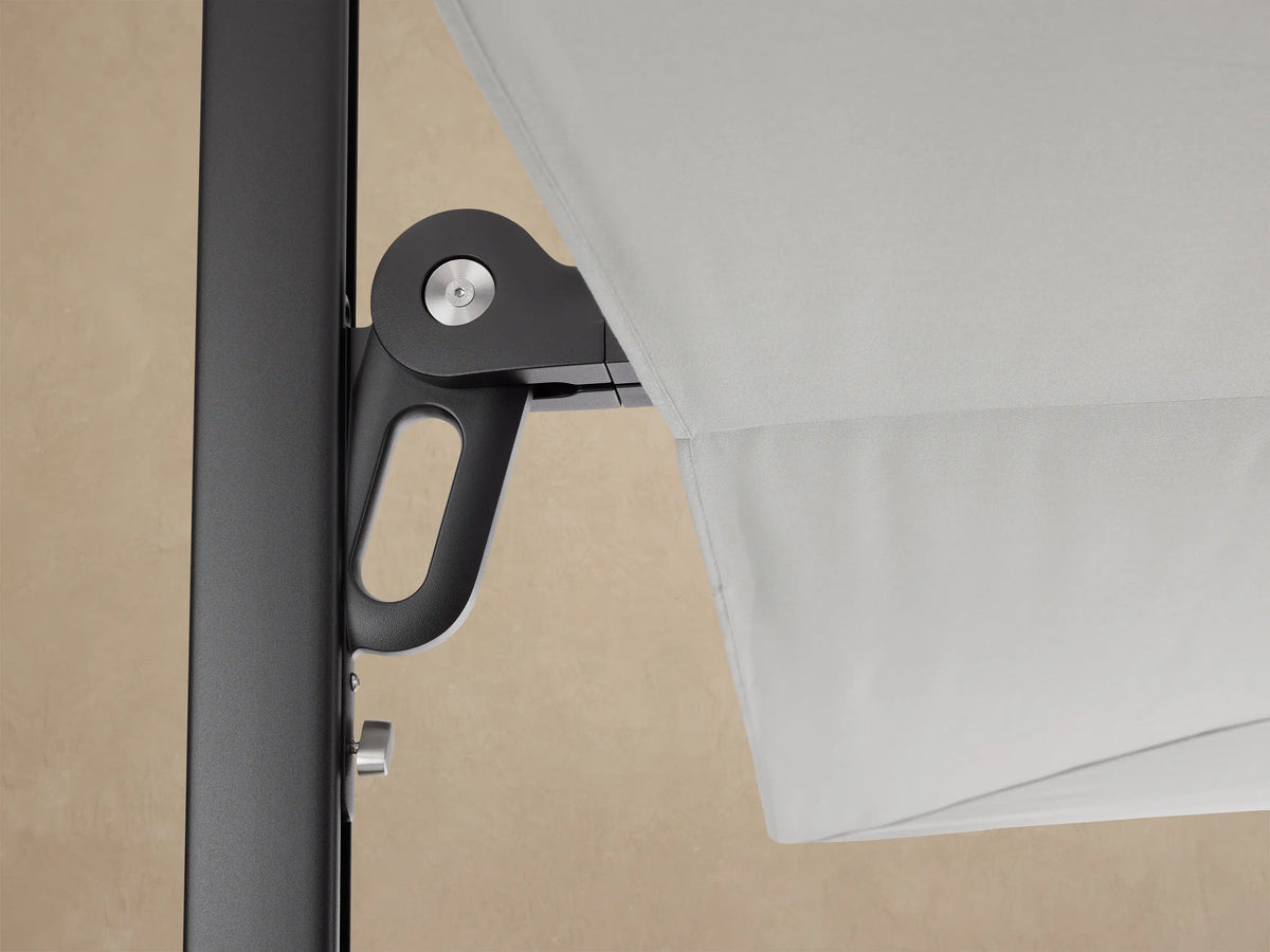 Collapsed Spectra Outdoor Square Umbrella in dark grey protective cover, standing vertically on a black wheeled base on a patio.
