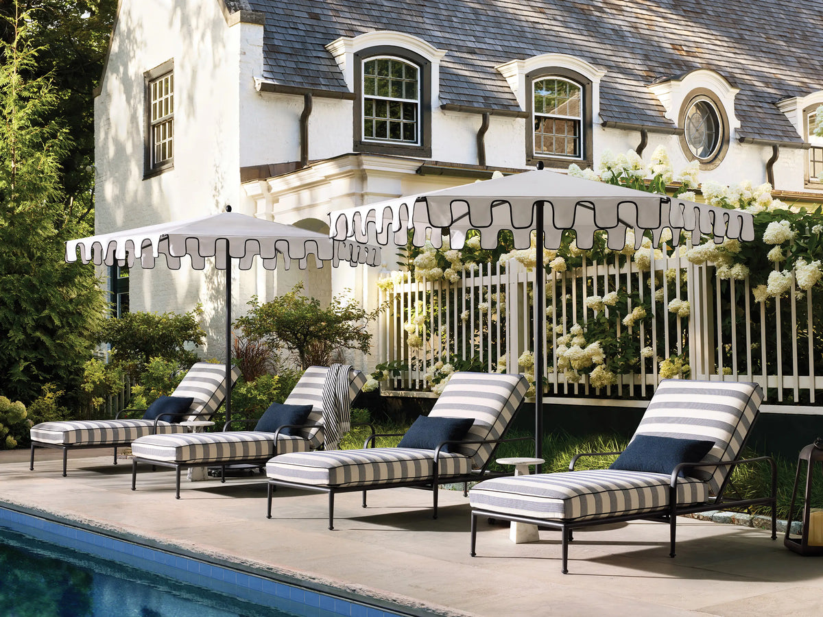 Side view of the Surrey Outdoor Chaise, featuring a black aluminum frame and navy and cream striped cushions with an adjustable back.