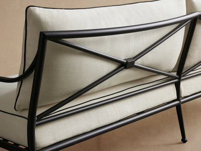 Surrey Outdoor Sofa with black aluminum frame and cream cushions with black piping, shown on a patio.