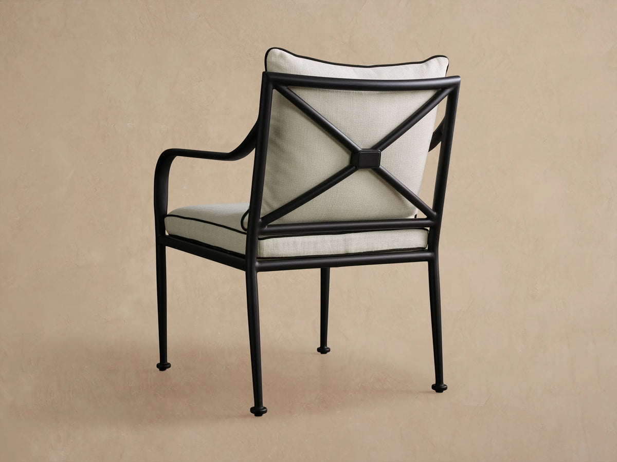 Surrey Outdoor Dining Arm Chair: black aluminum frame with X-back, light beige textured cushions, contrasting black piping.
