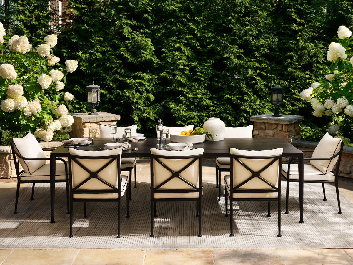 Surrey Outdoor Dining Side Chair with a sleek black metal frame, plump white cushions with black piping, on a tiled patio.