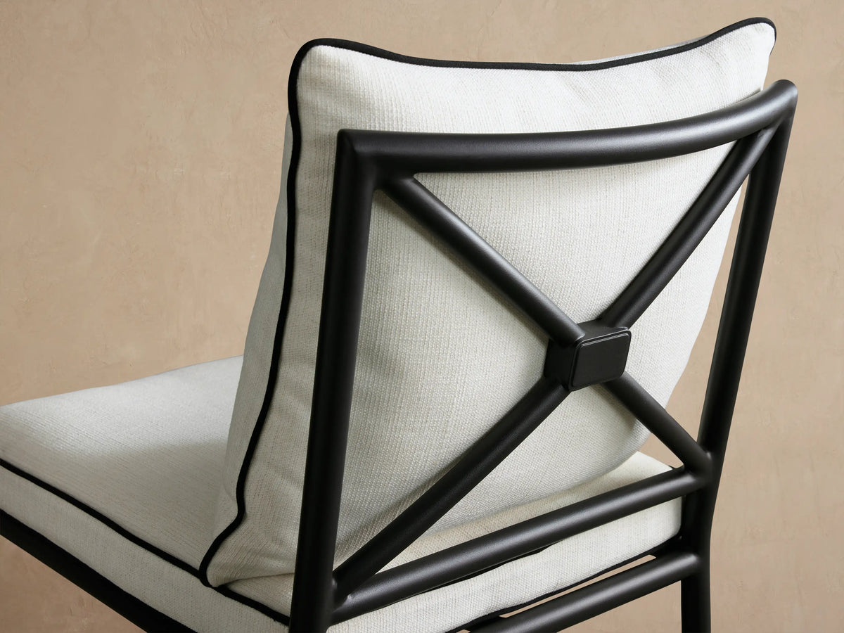 Surrey Outdoor Dining Side Chair, black metal frame, off-white seat and back cushions with black piping, front view.