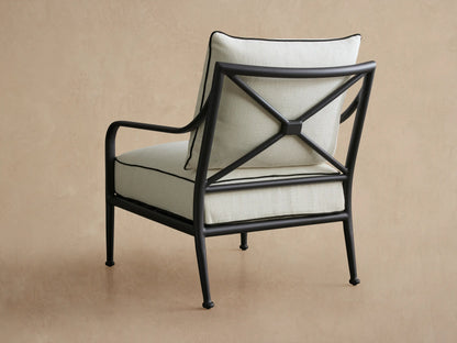 Close-up of Surrey Outdoor Lounge Chair backrest. Dark metal X-frame supports an off-white cushion with black piping.