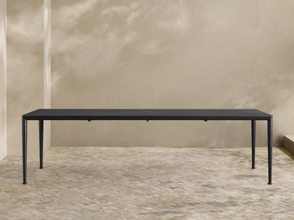 Dark gray powder-coated aluminum Surrey Outdoor Dining Table, long and rectangular, with an umbrella hole, in an outdoor patio.