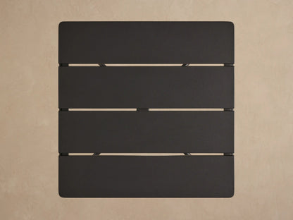 Surrey Outdoor End Table. Square charcoal gray slatted top with matte black aluminum frame, viewed from a slight angle.