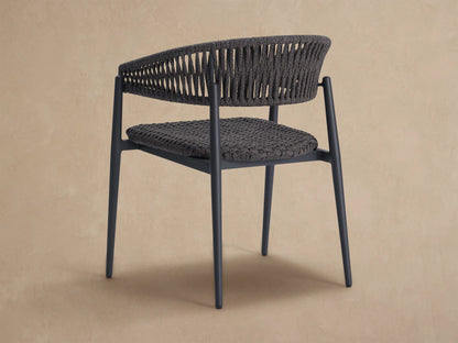 Close-up Talia Outdoor Dining Chair. Dark gray woven seat & open-patterned back. Black aluminum frame, neutral background.