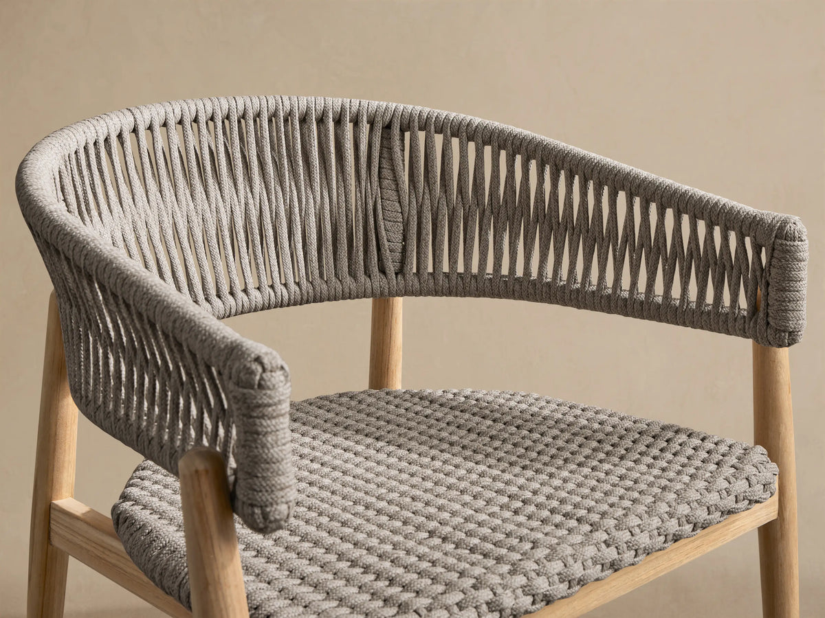 Talia Outdoor Teak Lounge Chair: light teak frame with woven gray rope back & seat, shown front-facing on a tiled floor.
