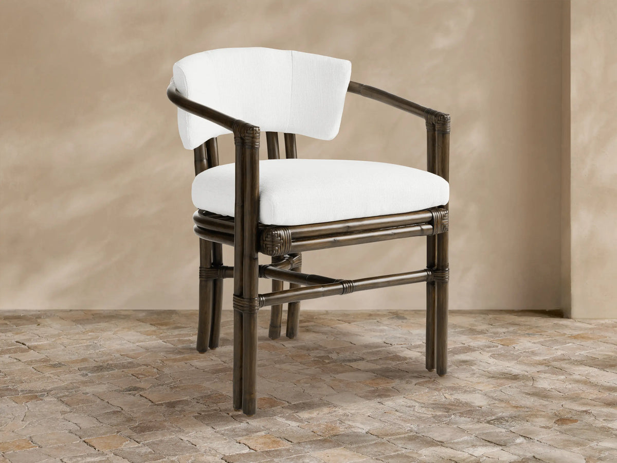 Dark brown rattan pole Van Sunroom Dining Chair with white cushions, slightly angled, on a light stone tile floor.