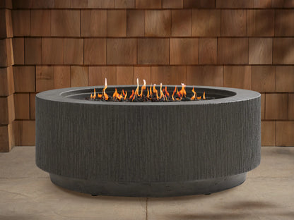 Wilmar Round Propane Fire Pit, dark gray textured concrete with active flames in a black lava rock bed, on a patio.