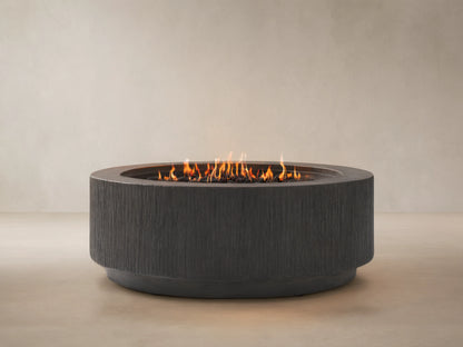 Wilmar Round Propane Fire Pit, dark gray textured concrete with active flames in a black lava rock bed, on a patio.