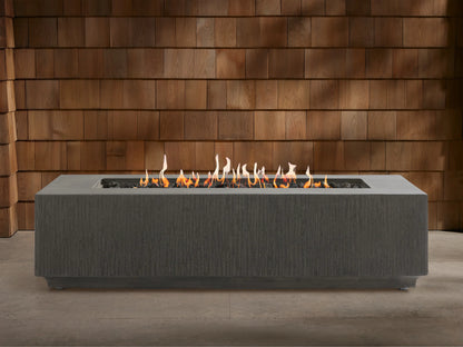 Wilmar Rectangular Propane Fire Pit, dark gray textured concrete, with bright flames rising from black lava rocks.