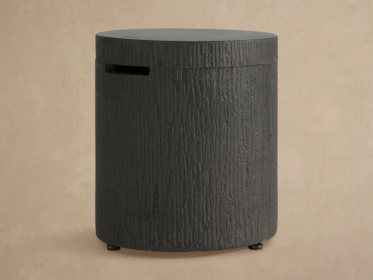 Cylindrical dark gray concrete Wilmar Fire Pit Tank Cover with bark-like texture, flat top, and horizontal slot.