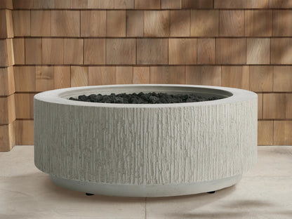 Wilmar Round Propane Fire Pit in Fog Chiseled, light gray concrete with textured sides, flames burning in black lava rocks.