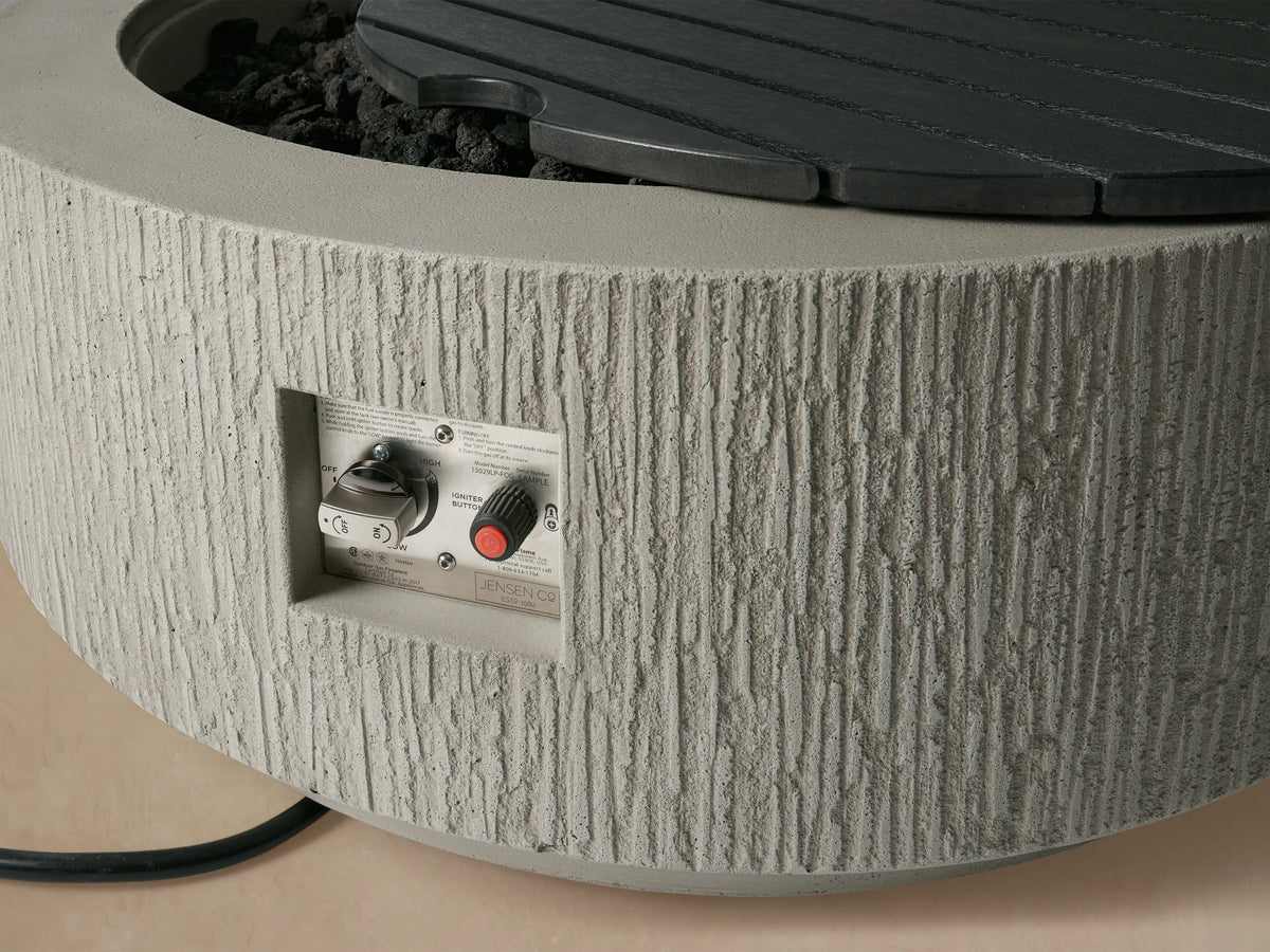 Round Wilmar Propane Fire Pit, 'Fog Chiseled' textured light grey concrete, with a dark slatted lid, on a plinth base.
