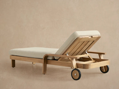 Zoe Outdoor Chaise, close-up. Teak wood frame, curved armrest, light beige cushion, and visible adjustable back hinge.