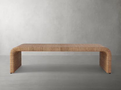 Zoya Sunroom Coffee Table made from woven natural abaca fiber, featuring a sleek rectangular design with curved edges on a gray floor.