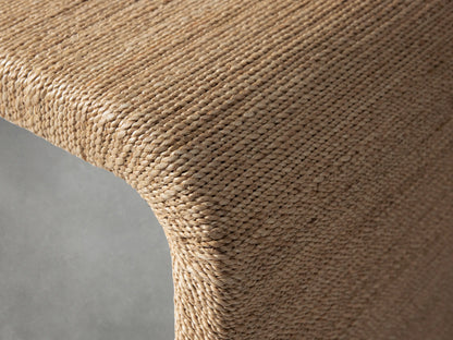 Zoya Sunroom Coffee Table made of woven natural abaca fiber. Rectangular shape with rounded edges on a gray background.