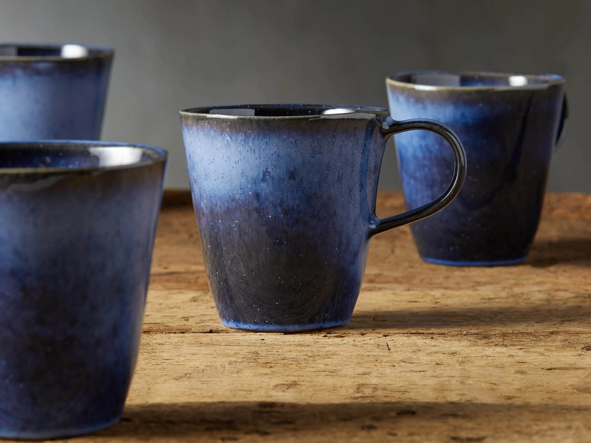 Twilight Mug in deep indigo stoneware with reactive glaze, subtle color variations, curved handle, on wooden surface.