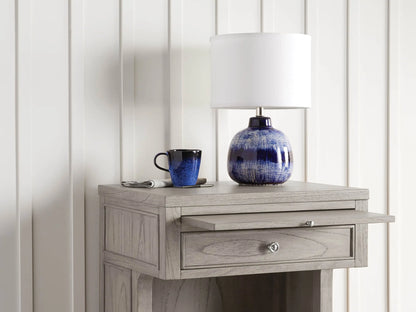 Four indigo stoneware mugs with rich blue reactive glaze, handcrafted texture, placed on a wooden surface, varying in shade.