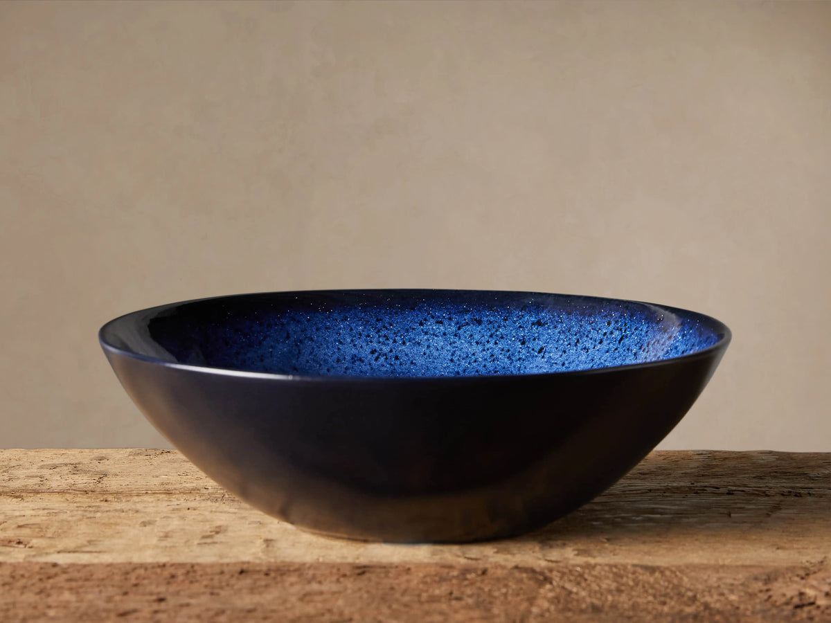 Twilight Serving Bowl with rich indigo reactive glaze, handcrafted in stoneware. Blue interior with slight color variance, set on wooden surface.